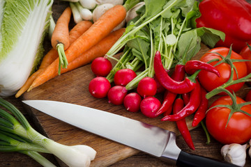 Fresh vegetables on kitchen board with knife 