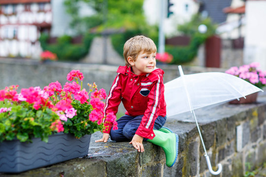 Little blond kid boy with big umbrella outdoors