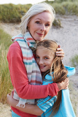 Grandmother With Granddaughter Standing On Beach