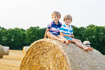 Naklejka na ściany i meble Two little children and friends with hay stack or bale