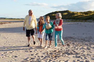 Grandparents Playing Soccer With Grandchildren On Beach