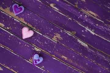 Сердечки из сиреневого/фиолетового и розового фетра ручной работы, вышитые бисером, на старом/вытертом  деревянном полу  - obrazy, fototapety, plakaty
