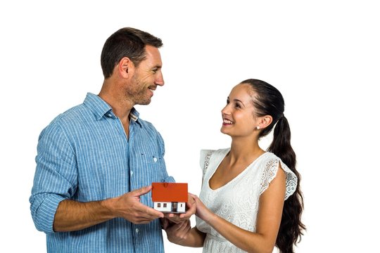 Face to face couple holding house model 