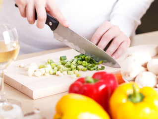 Obraz na płótnie Canvas Close up of female cutting vegetables on a kitchen cutting board