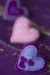 Сердечки из сиреневого/фиолетового и розового фетра ручной работы, вышитые бисером, на старом/вытертом  деревянном полу 