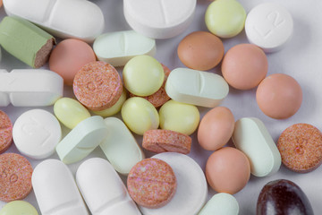 Many type of drugs pills capsules and medicine poring from the bottle with white isolation background. Medical manufacturing industry concept.