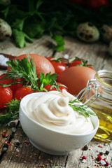 Homemade mayonnaise sauce in a white bowl, jar with olive oil, e