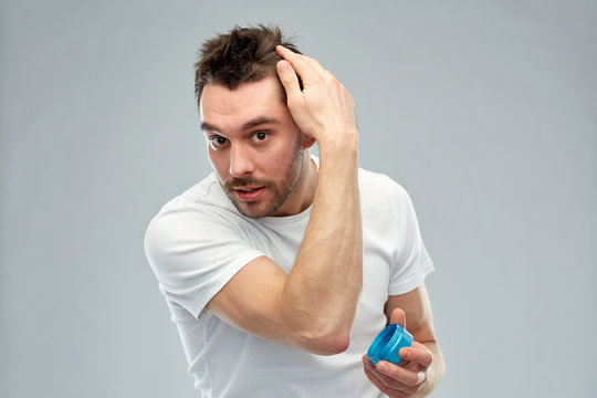 happy young man styling his hair with wax or gel