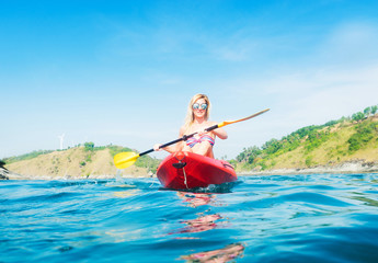 Woman exploring calm tropical bay by kayak.
