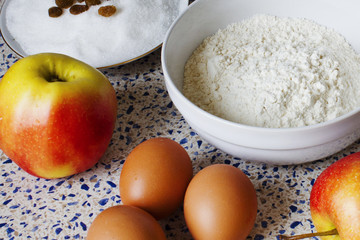Ingredients for apple pie on the kitchen table. Flour, sugar, raisins, eggs and apples for homemade pastries.