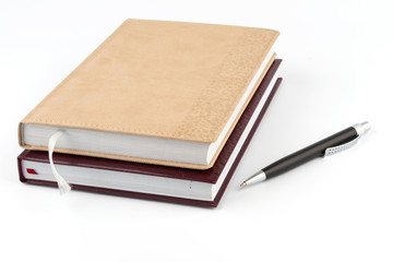 Two diary stacked lying next to a black pen.