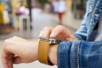 Woman using smartwatch in the street. Closeup on hands