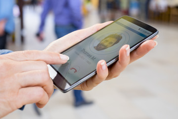 Woman answering to a friend on mobile phone. Blur people background
