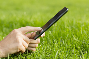 A woman texting a message on mobile phone chilling on the grass