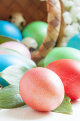 Multi-colored Easter eggs roll out of a wicker basket, festive s