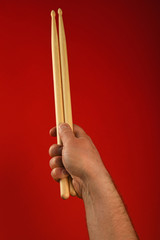 Man hand with two drumsticks over red