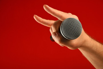 Man hand with microphone and devil horns over red