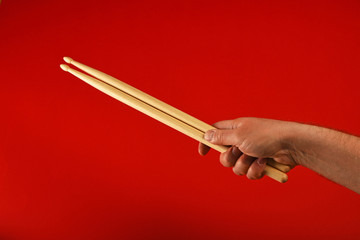 Man hand with two drumsticks over red