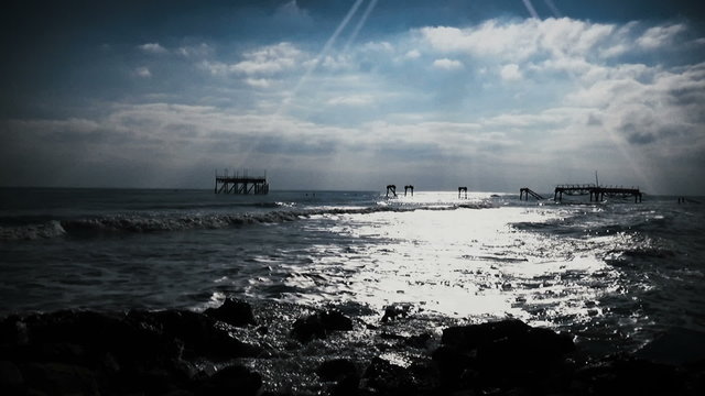 Slow motion long shot pan right of sea waves breaking into ruined oil rig bridge in Shabla, Bulgar