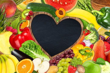 various tasty fruits and vegetables on wooden heart shaped blackboard 