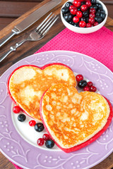 Couple of homemade colored heart shaped pancakes with berries