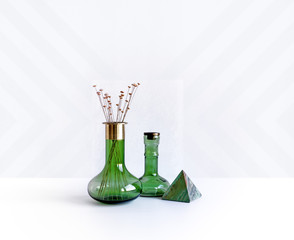 Still life of two green glass vases and marble pyramid.