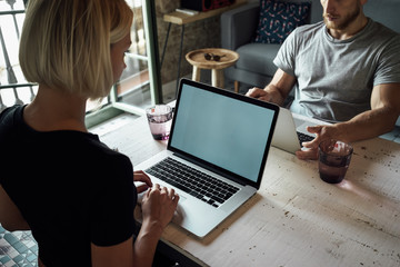 Creative female freelancer sitting front laptop computer with blank copy space screen for your information. young man and young woman working opposite each other with laptops
