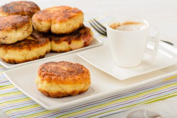 Cheese pancakes on white plate and cup of coffee.