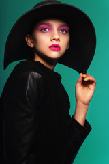 Portrait of a beautiful girl in a hat with bright makeup in studio