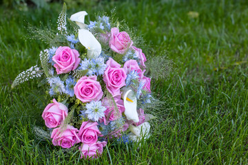 Obraz na płótnie Canvas A bridal bouquet consisting of pink roses on a green bed of grass
