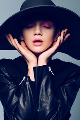 Portrait of a beautiful girl in a hat with eyes closed, posing in studio