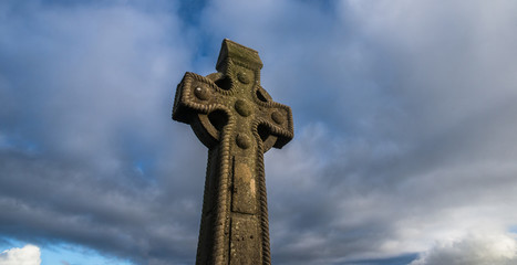 celtic cross gravestone with dramatic stormy sky background