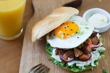 A delicious asian style hamburger garnished with lettuce, onion and topped with fried egg