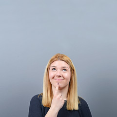 Fototapeta premium Portrait of woman coming up with an idea against gray background