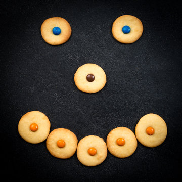 Smiley face of childish cookies on black stone background