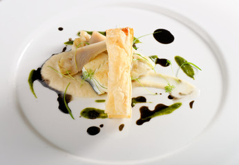 Fine dining, baked cod fillet with spinach sauce and roasted onions