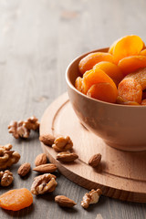 Dried apricots in a bowl on wooden board