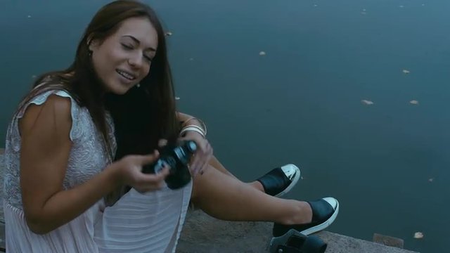 Young attractive Caucasian woman taking pictures with vintage camera on an old pier