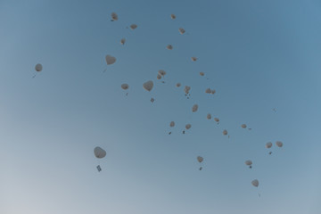 In den blauen Himmel aufsteigende weiße Luftballone mit Grußkarten am Band