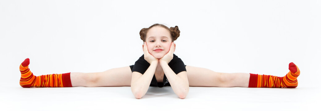Little girl in black dress doing gymnastic split on white backgr