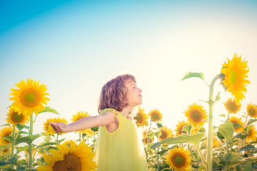 Happy child having fun in spring sunflower field