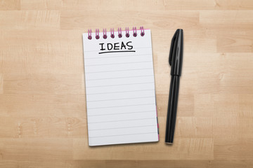 Ideas note pad with pen on wood