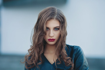 Closeup city portrait of young stylish woman with bright trendy makeup wavy hairstyle in black leather jacket with shallow depth of field