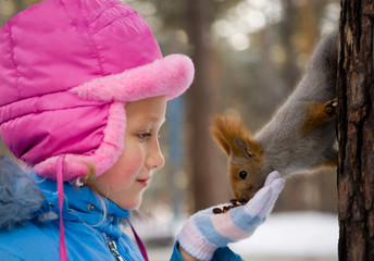 Little Girl Feeding a Squirrel in the Winter Forest.