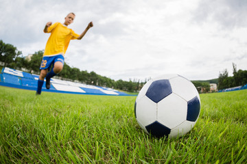Boy playing football at the stadium. Natural lawn.