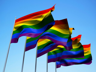Rainbow flags waving in the wind with a blue sky background. 3d illustration