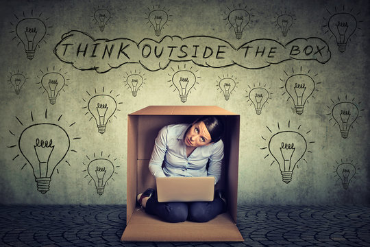 Think outside the box concept. Woman sitting inside box using working on laptop computer
