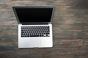 An open silver laptop on the wooden background