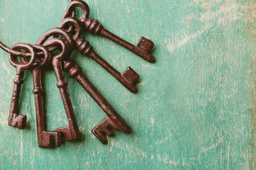 Bunch of old keys on green scratched wooden background, close up