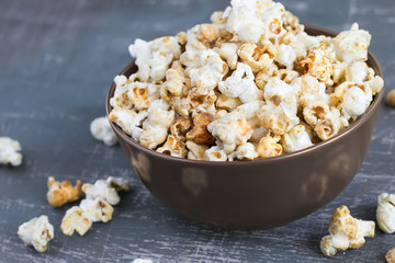 Sweet caramel popcorn in a  bowl on a dark blue background